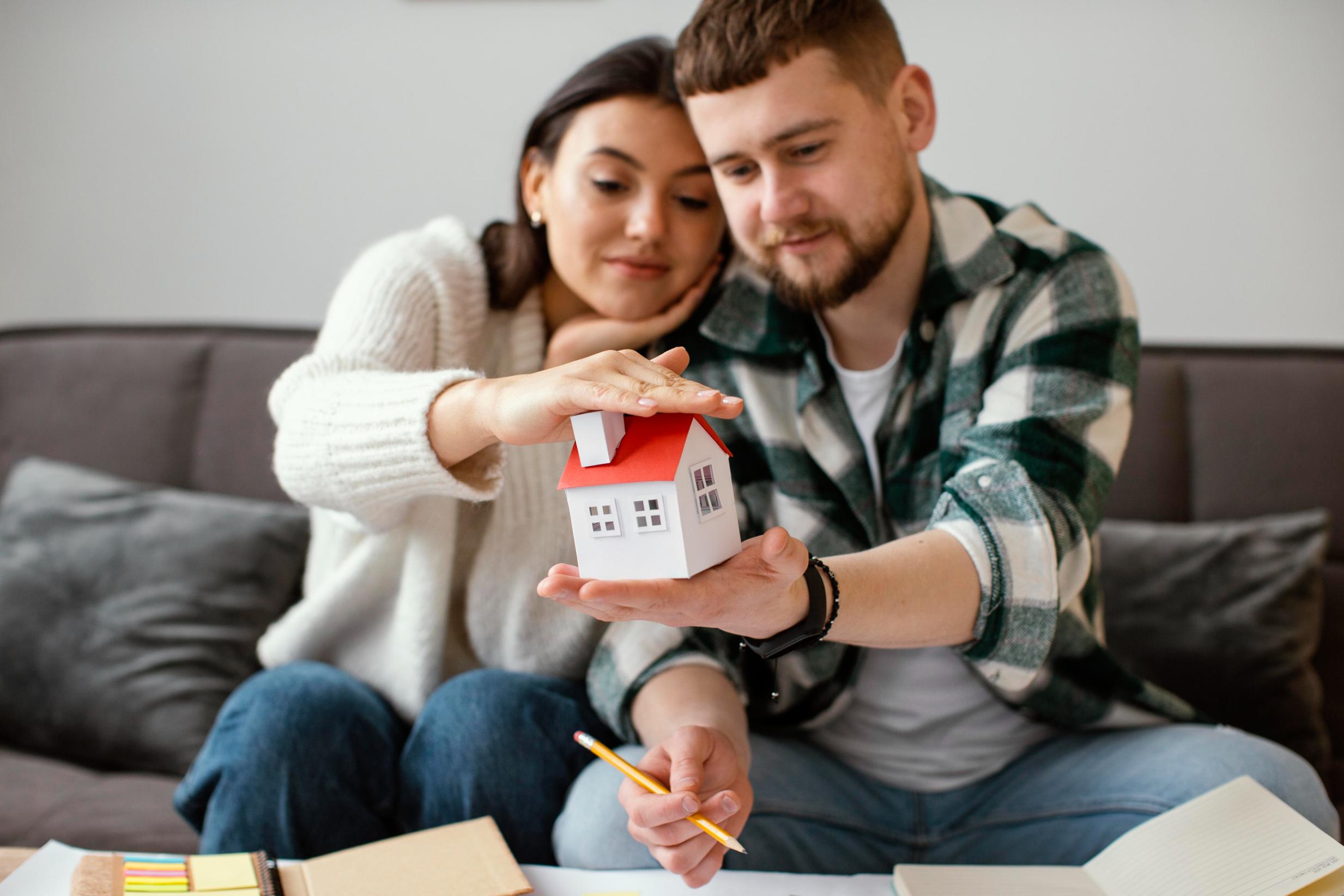 Couple holding a small house model representing first time homebuyers in Texas exploring affordable mortgage and financing options.