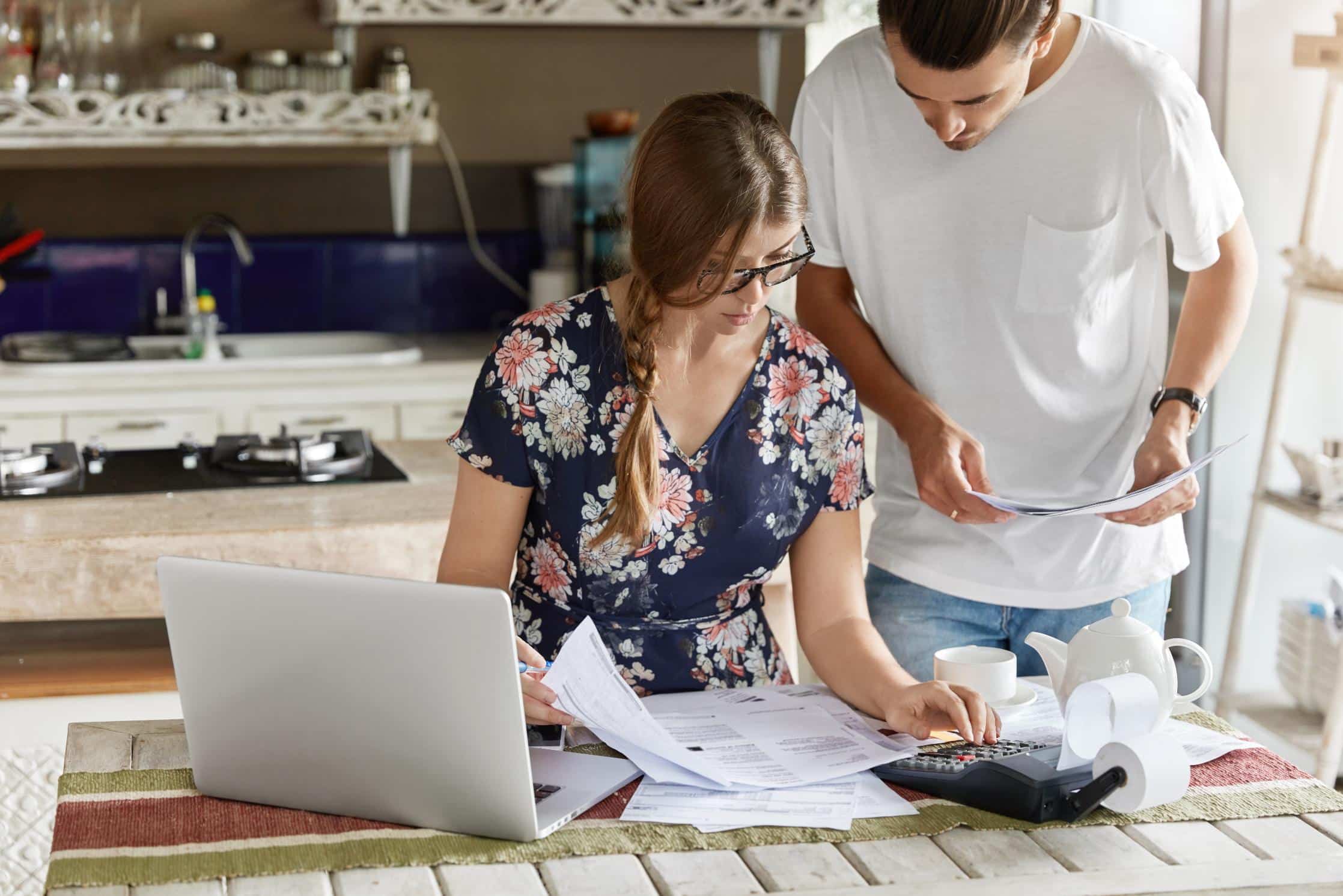 Couple reviewing finances and documents for FHA loans in Texas while calculating budget and planning home purchase.