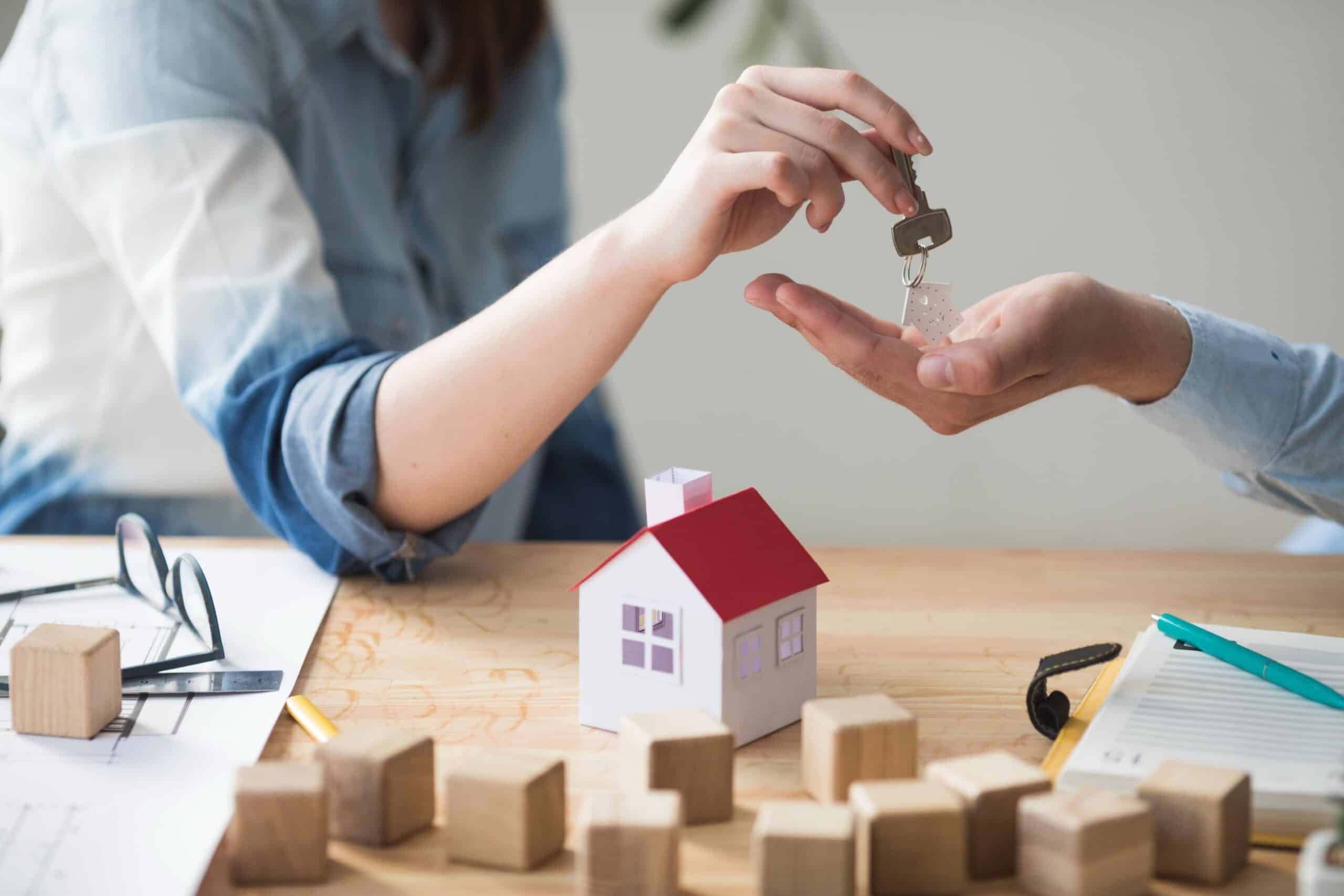 Person handing house keys to buyer with model home representing FHA Homebuyers in Texas purchasing a new property.