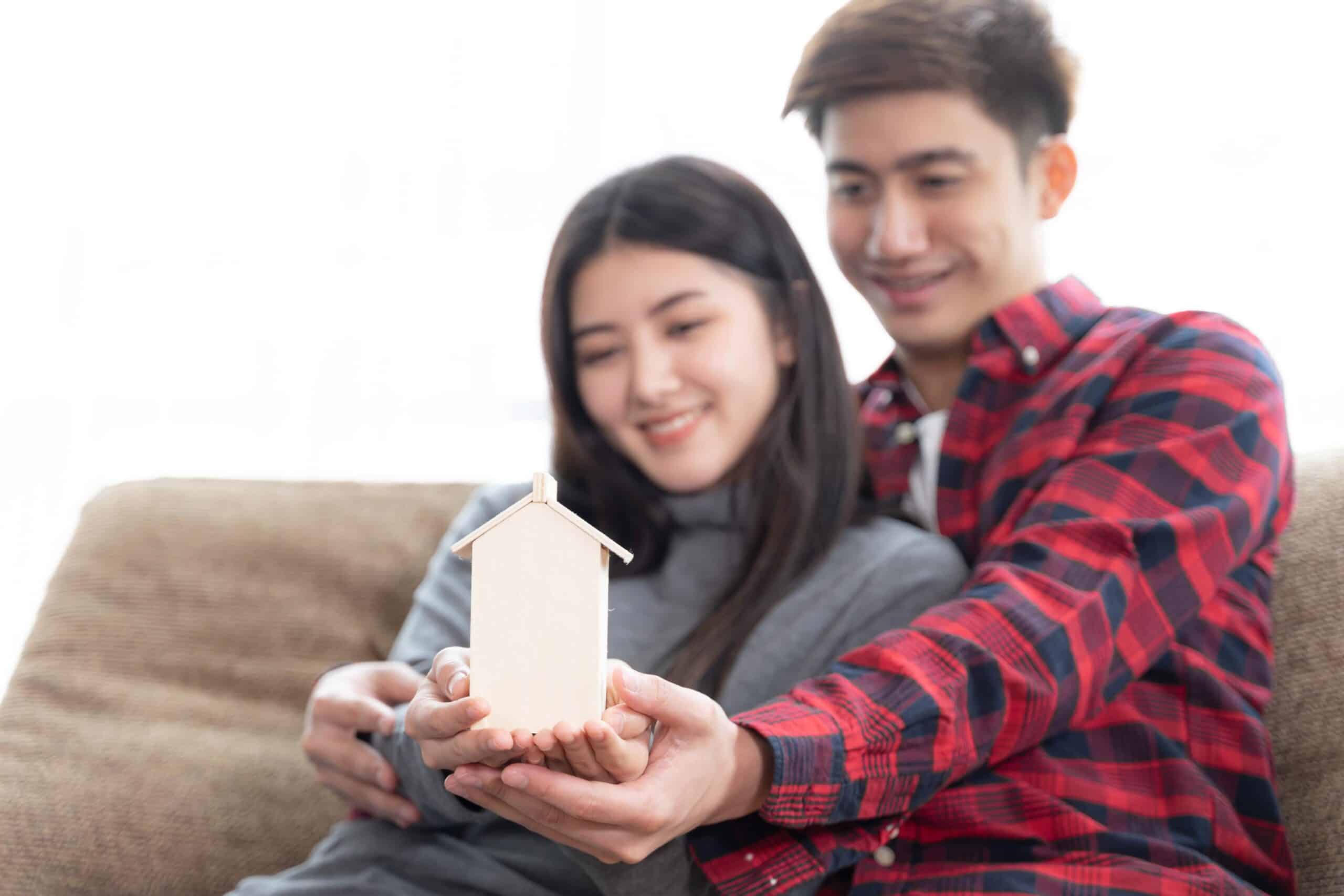 Happy first-time homebuyers holding a house model and planning their future homeownership