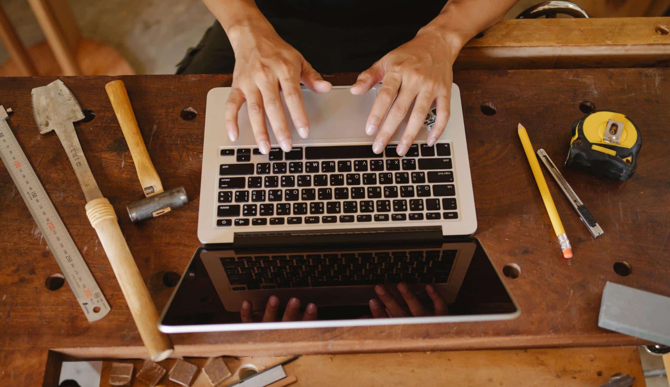 Self-employed professional working on a laptop with tools nearby, representing self-employed mortgage loan programs